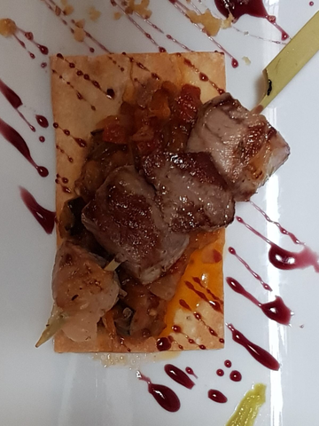 TAPA: OBLEA DE PAN DE MIGA DURA, PISTO, BROCHETA DE CORDERO ADOBADO Y REDUCCIÓN DE VINO TINTO.