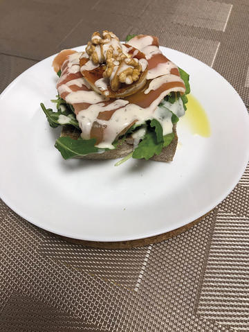 Tosta de pan moreno con rúcula, lacón e rulo de cabra en salsa de iogur